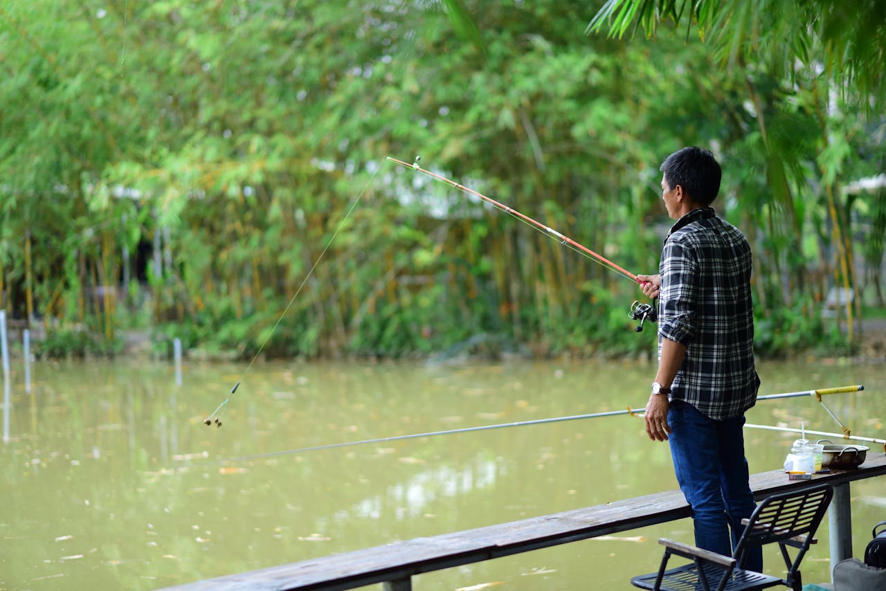 man-fishing-by-a-tranquil-pond-in-nature-34252127